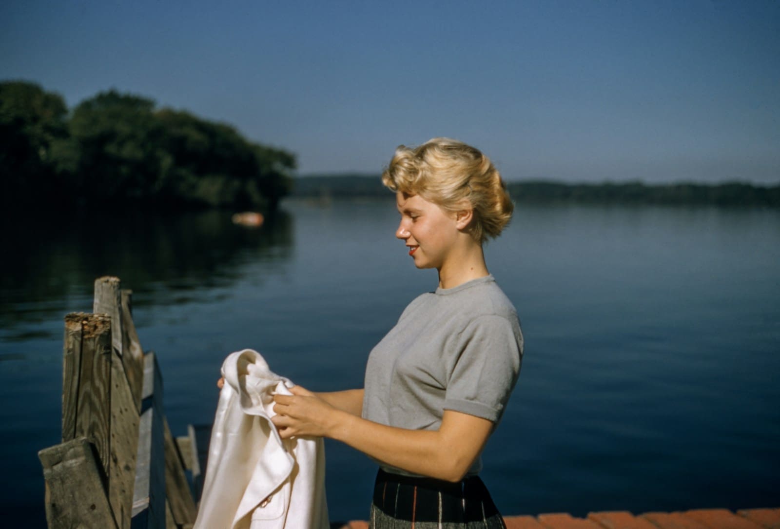 Photo by Les Anderson woman holding white textile standing beside body of water