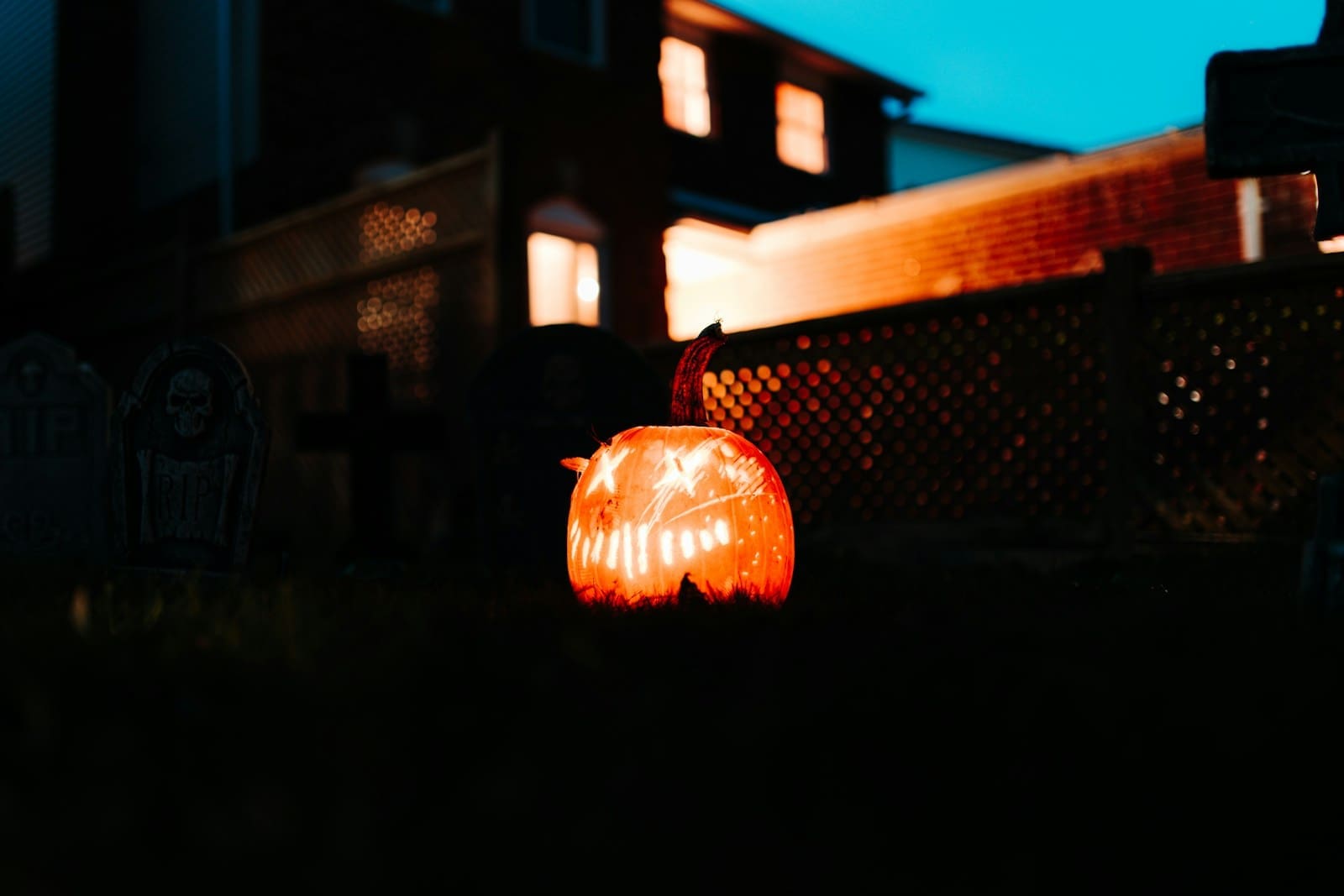 Photo by Dillon Kydd a carved pumpkin sitting on the ground in front of a house