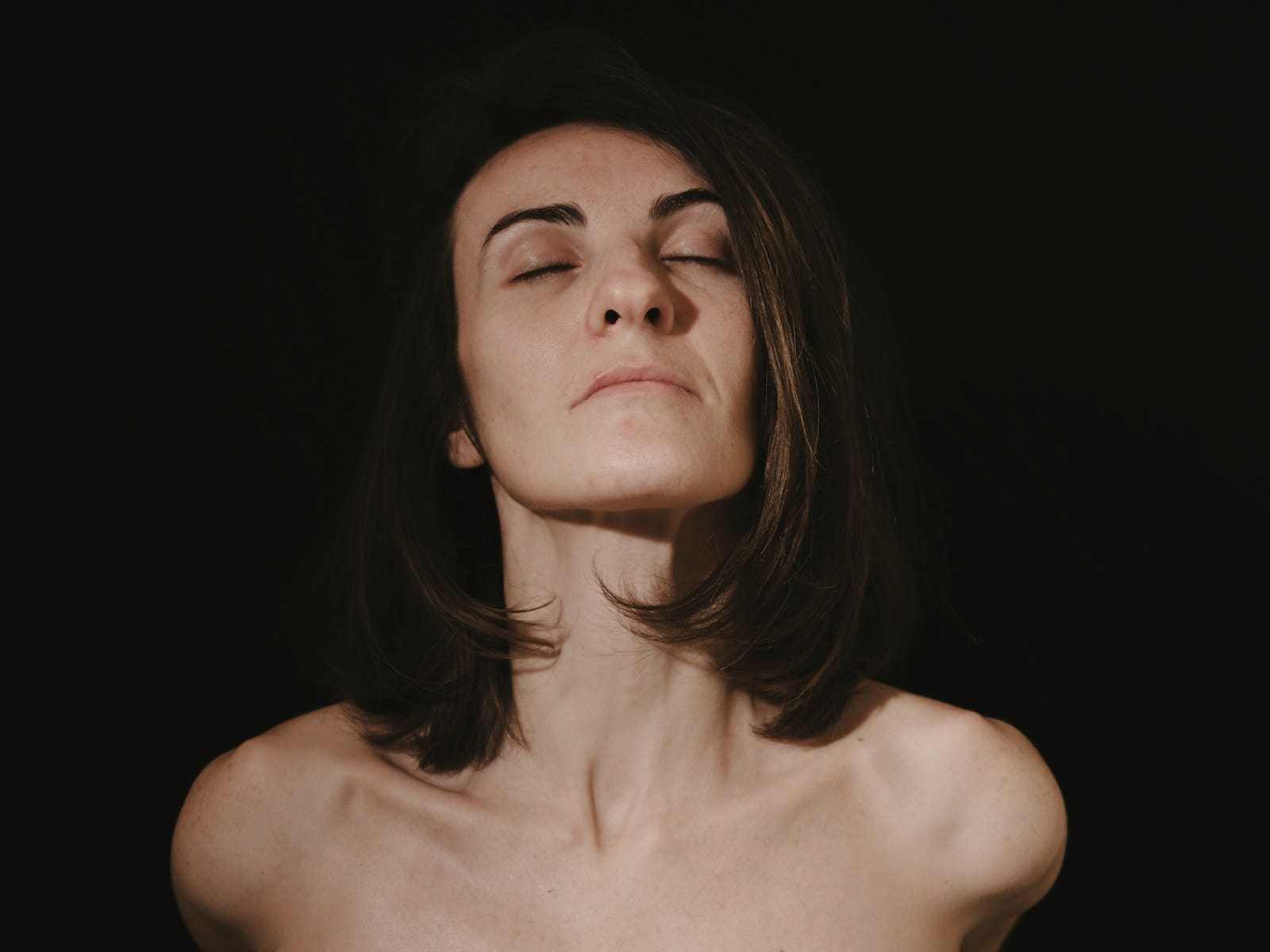 Photo by engin akyurt a woman with her eyes closed in the dark, coming into the light of a life without PCOS