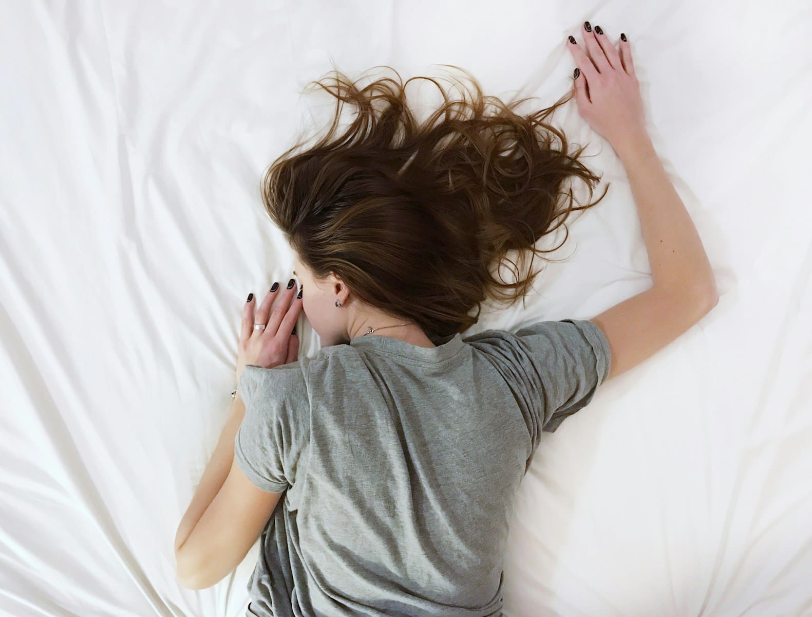 Photo by Vladislav Muslakov woman laying on bed in pain with PCOS. Even after hysterctomy PCOS can