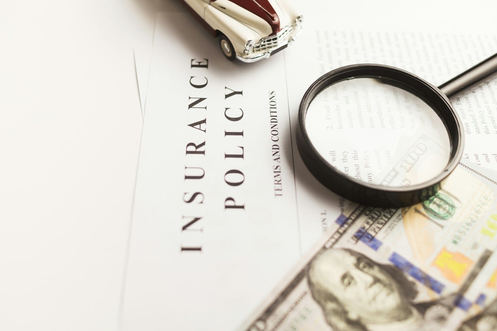 Photo by Vlad Deep a magnifying glass sitting on top of a piece of paper that says Insurance Policy.